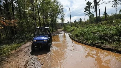 UTV driving through a large mud puddle on the trail in Langlade County